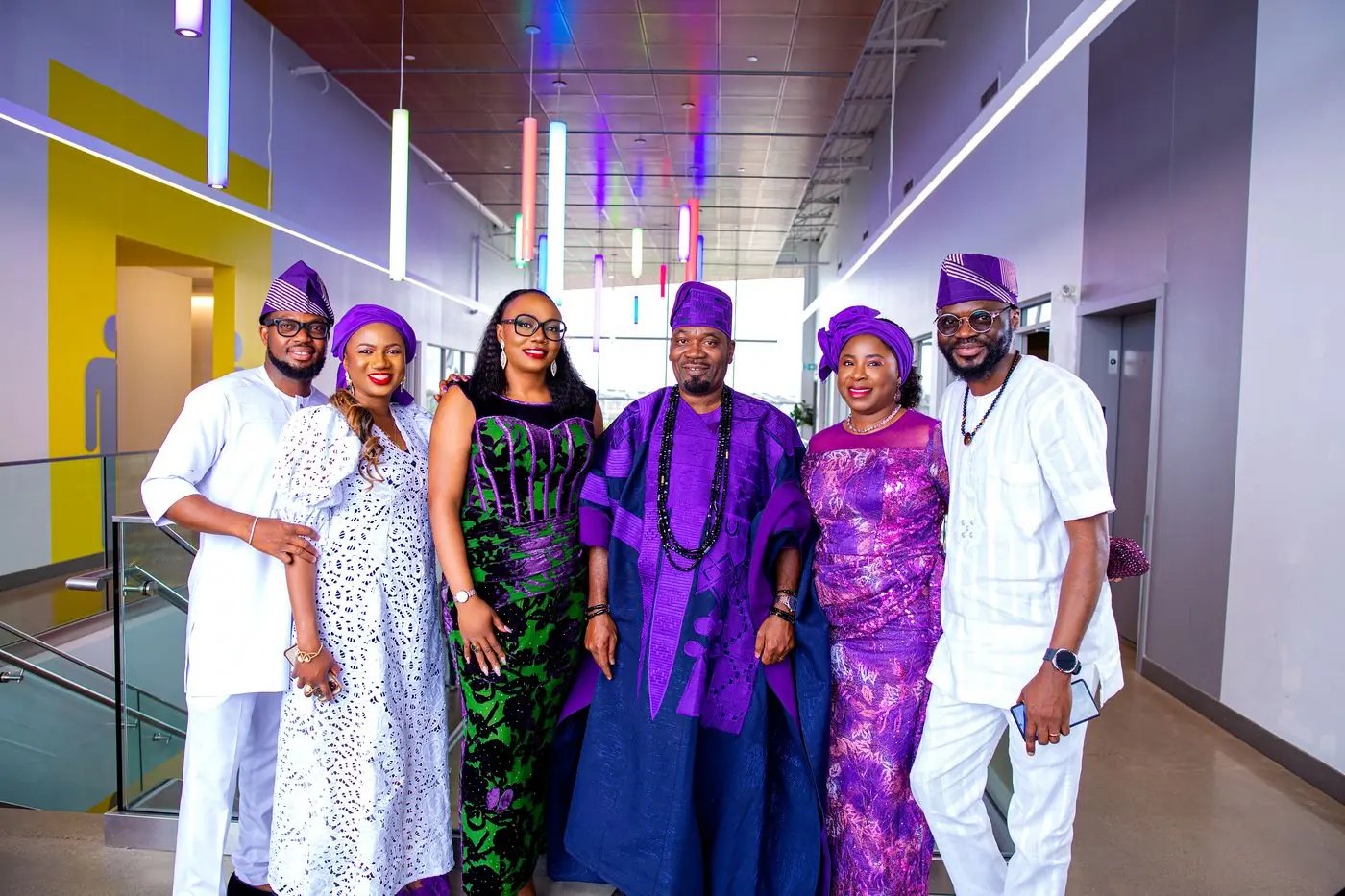 Extended family group photography in Calgary: six family members in matching purple and white aso-ebi at a family celebration