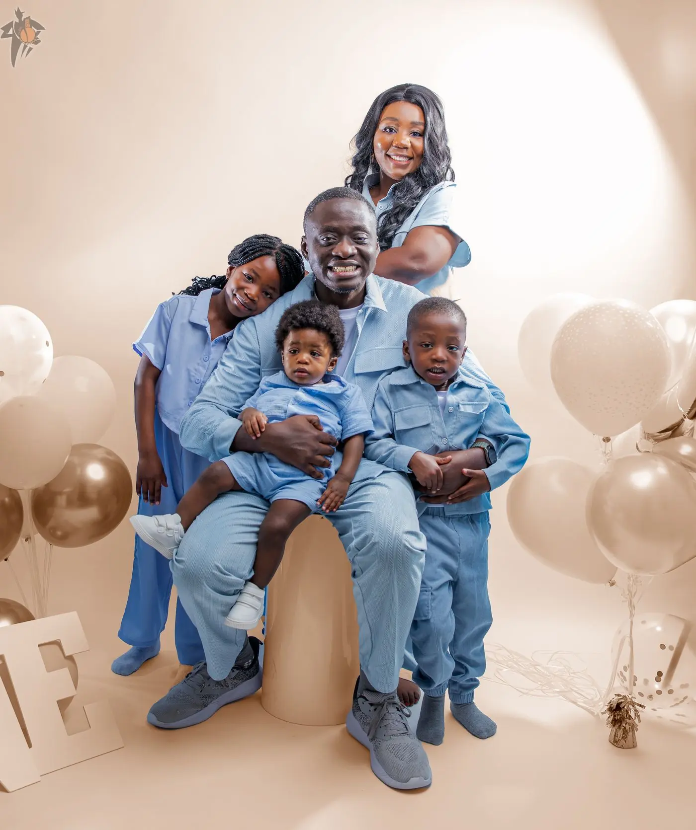 Family photography in Calgary by Onilu Prime: parents and four children in coordinated blue outfits on a beige studio backdrop