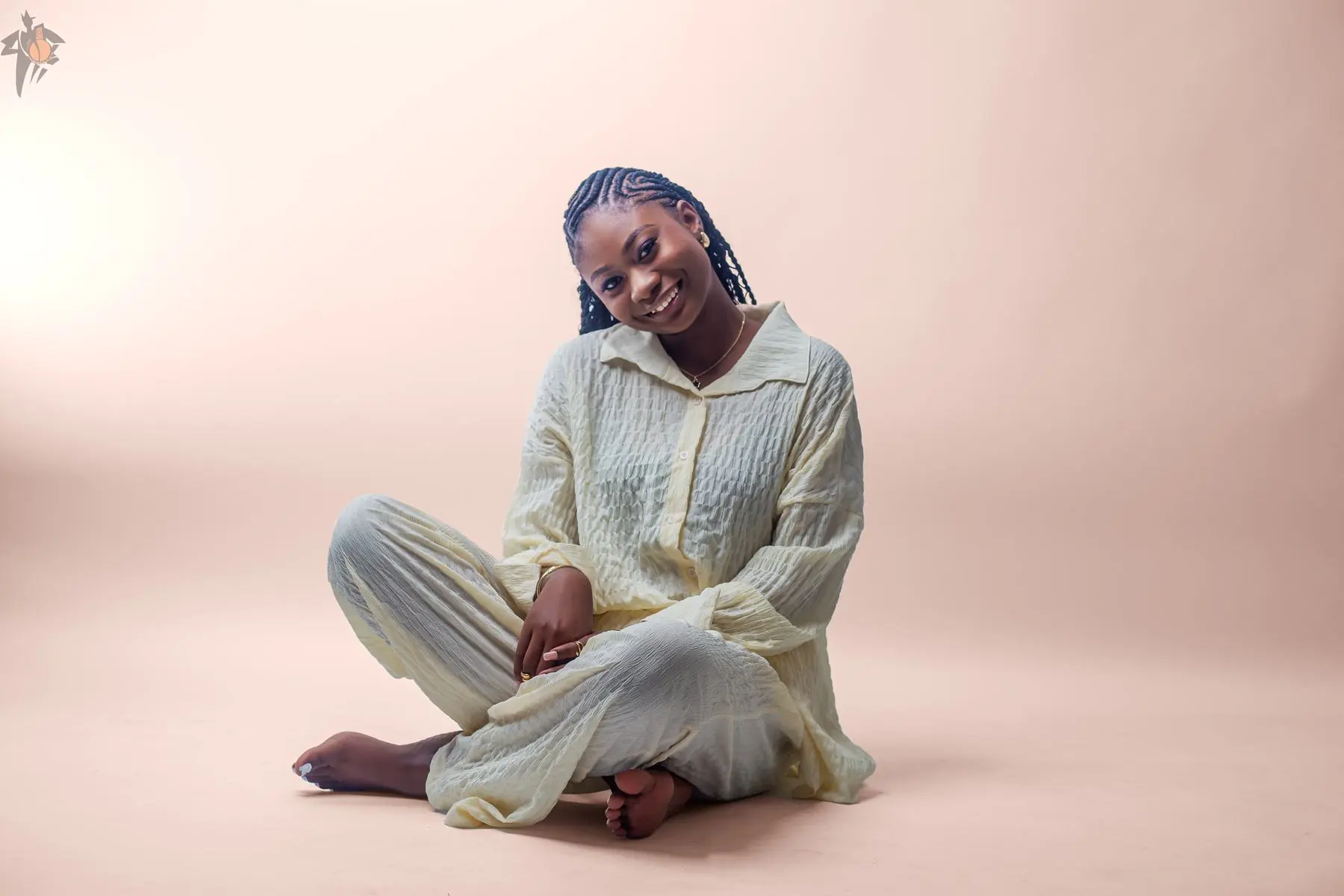 Calgary portrait photography by Onilu Prime: young woman seated in a studio session on a warm backdrop