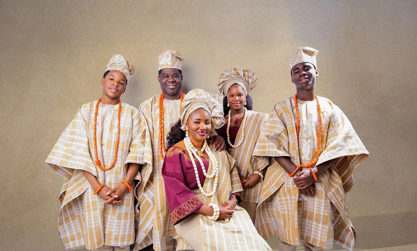 Family group portrait at a Nigerian traditional wedding in Calgary: five family members in matching aso-oke agbada, gele and coral beads