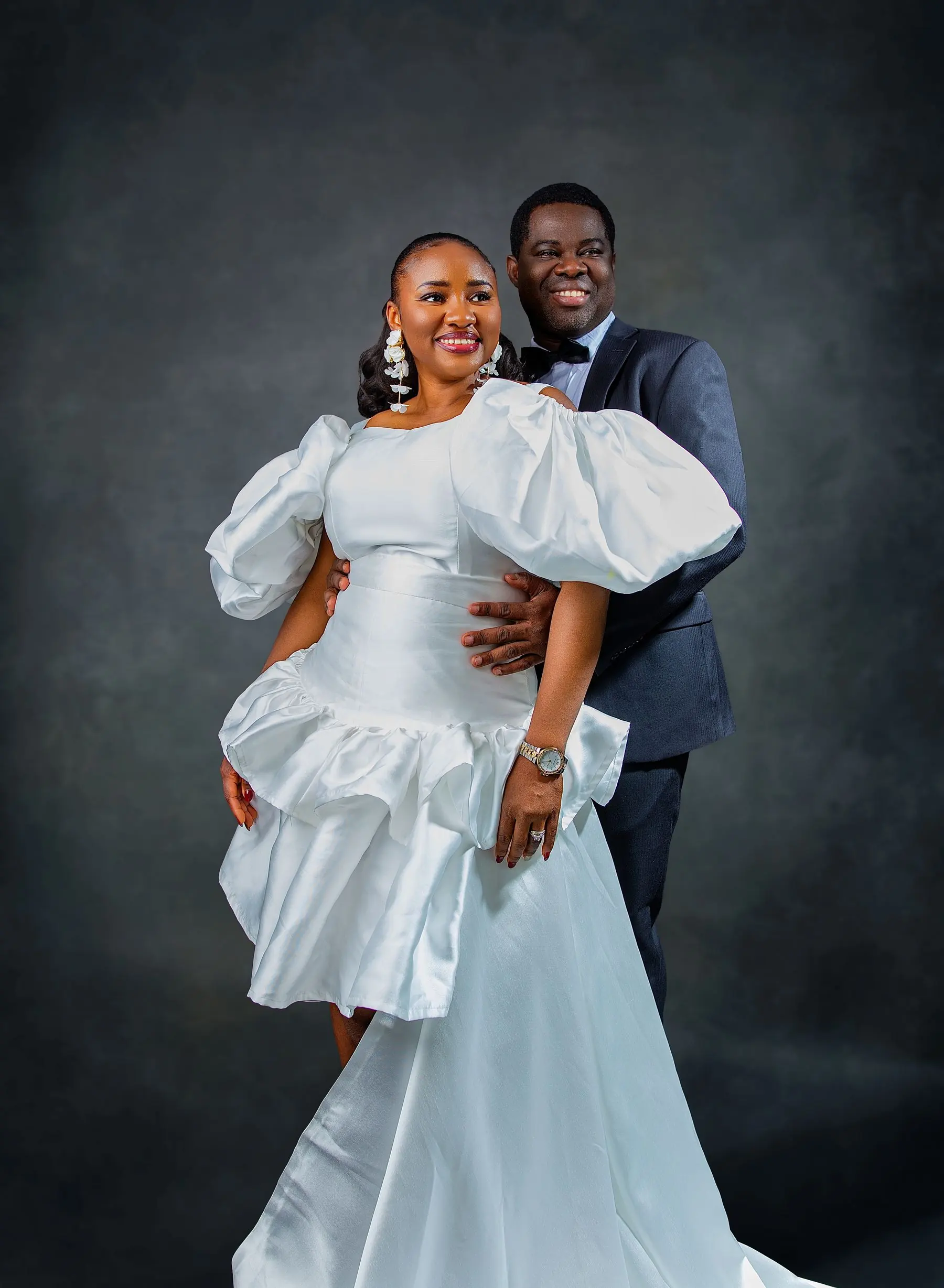 Calgary wedding photography by Onilu Prime: bride in a white gown with full sleeves and groom in a navy tuxedo, studio portrait